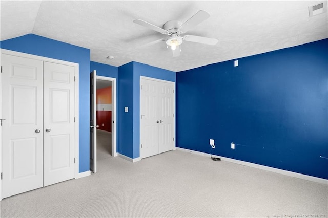 unfurnished bedroom featuring lofted ceiling, a textured ceiling, ceiling fan, and light carpet