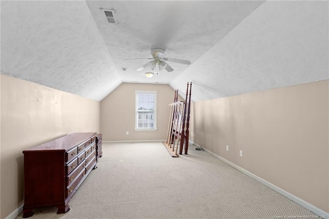 additional living space with lofted ceiling, a textured ceiling, ceiling fan, and light colored carpet