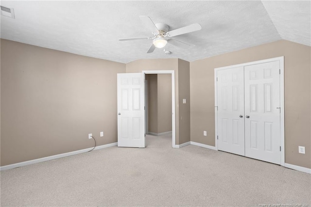 unfurnished bedroom with a textured ceiling, light colored carpet, ceiling fan, and a closet