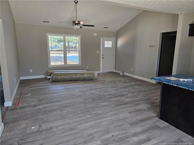 entrance foyer featuring lofted ceiling, ceiling fan, a textured ceiling, wood finished floors, and baseboards