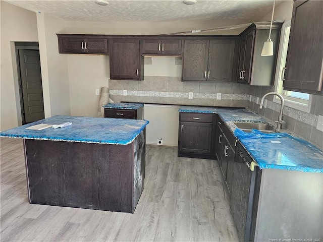 kitchen with dark brown cabinetry, a sink, dishwasher, light wood finished floors, and tasteful backsplash