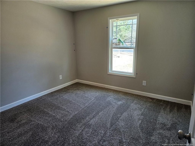 empty room with dark colored carpet and baseboards