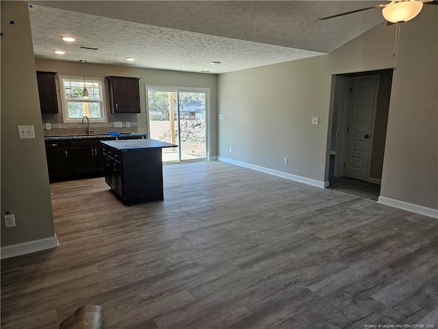 kitchen featuring a kitchen island, baseboards, a sink, and wood finished floors