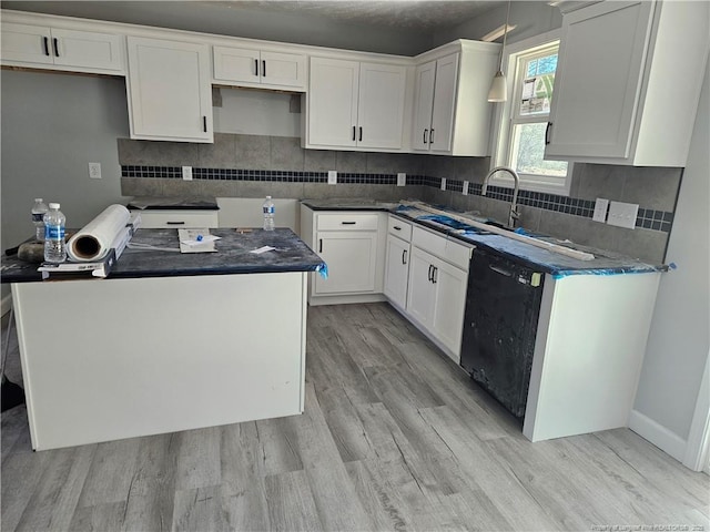 kitchen with white cabinets, light wood-style floors, black dishwasher, and tasteful backsplash