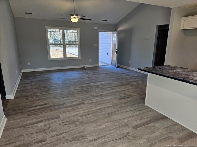 unfurnished living room featuring dark wood finished floors, lofted ceiling, visible vents, a ceiling fan, and baseboards