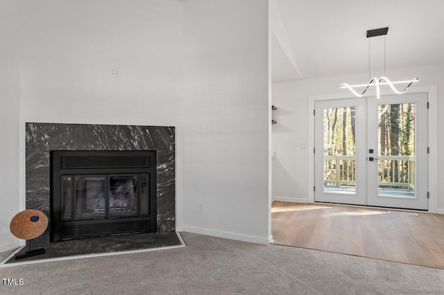 unfurnished living room featuring carpet floors, a high end fireplace, french doors, and vaulted ceiling