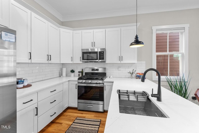 kitchen featuring hanging light fixtures, light hardwood / wood-style flooring, stainless steel appliances, and white cabinets