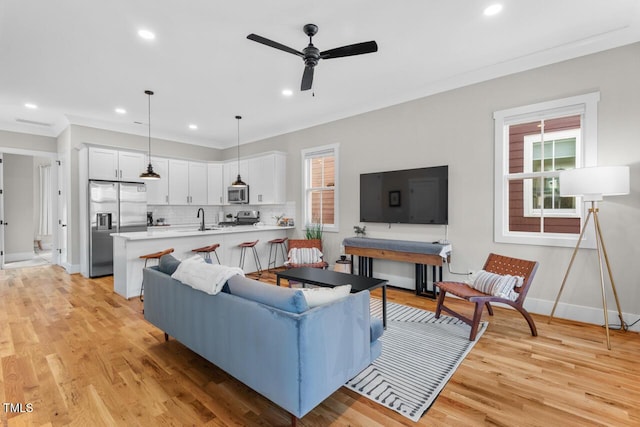 living room featuring crown molding, ceiling fan, sink, and light hardwood / wood-style floors