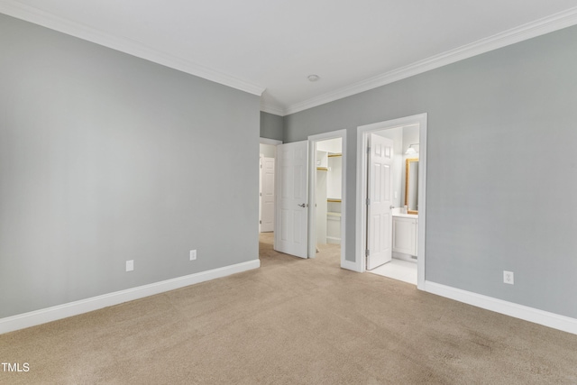 unfurnished bedroom with light carpet, connected bathroom, a spacious closet, and crown molding