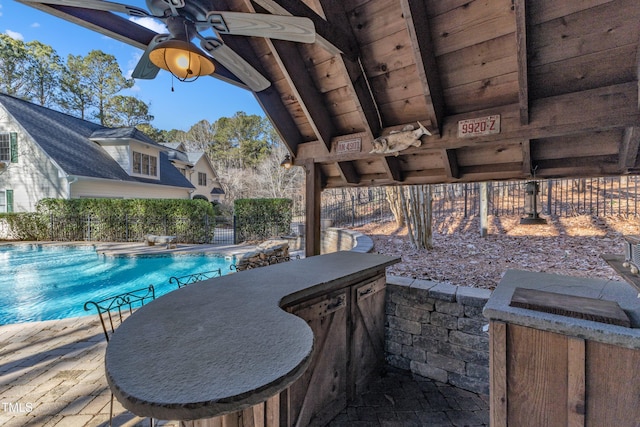 view of swimming pool with ceiling fan, an outdoor bar, and a patio