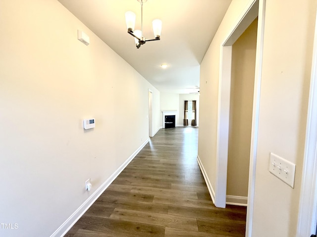 hallway with an inviting chandelier and dark wood-type flooring