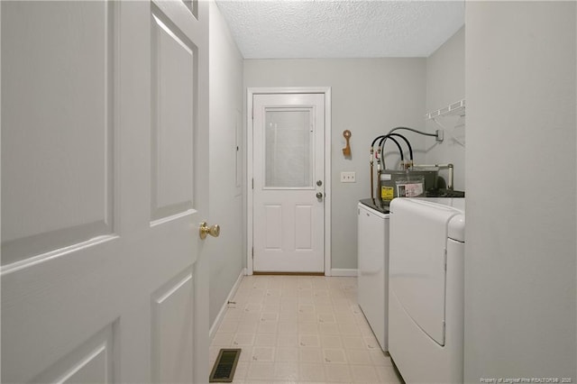 laundry area with a textured ceiling and washer and clothes dryer