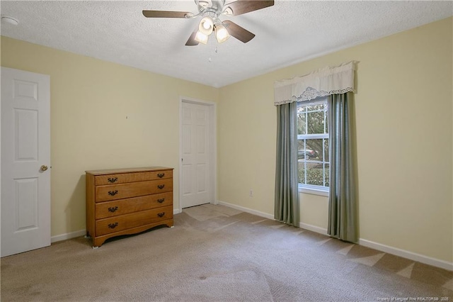 unfurnished bedroom featuring ceiling fan, light carpet, and a textured ceiling