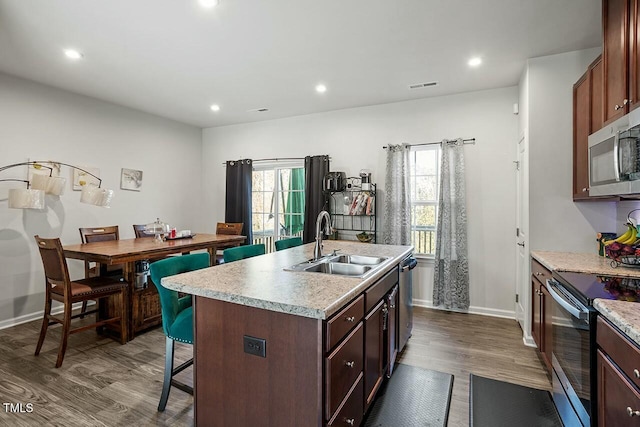 kitchen featuring appliances with stainless steel finishes, sink, dark hardwood / wood-style flooring, and a kitchen island with sink