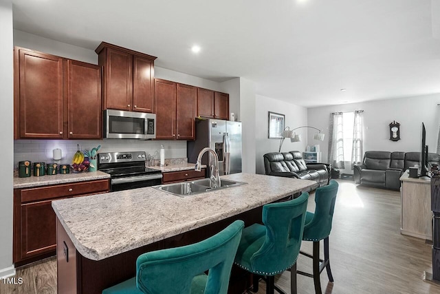 kitchen with a kitchen breakfast bar, appliances with stainless steel finishes, sink, and a center island with sink