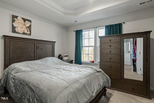 carpeted bedroom with a tray ceiling and ornamental molding