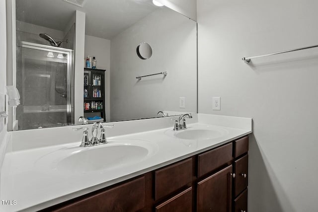 bathroom featuring a shower with shower door and vanity