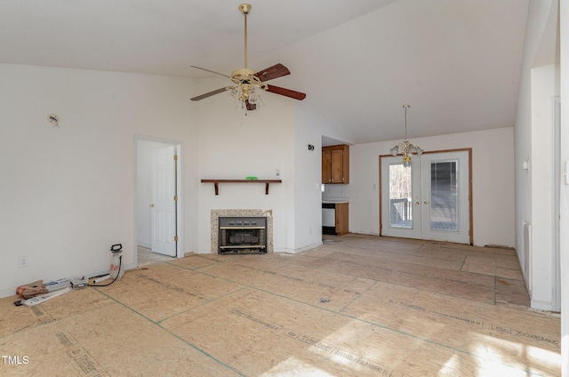 unfurnished living room featuring ceiling fan, a fireplace, french doors, and vaulted ceiling