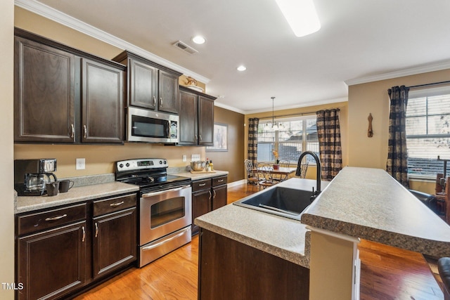 kitchen featuring stainless steel appliances, a center island with sink, sink, and dark brown cabinets