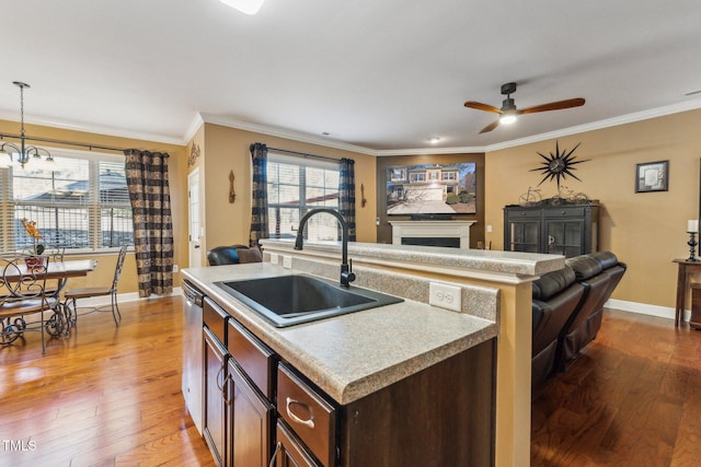 kitchen featuring decorative light fixtures, a center island with sink, crown molding, wood-type flooring, and sink