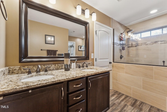 bathroom with a tile shower and vanity