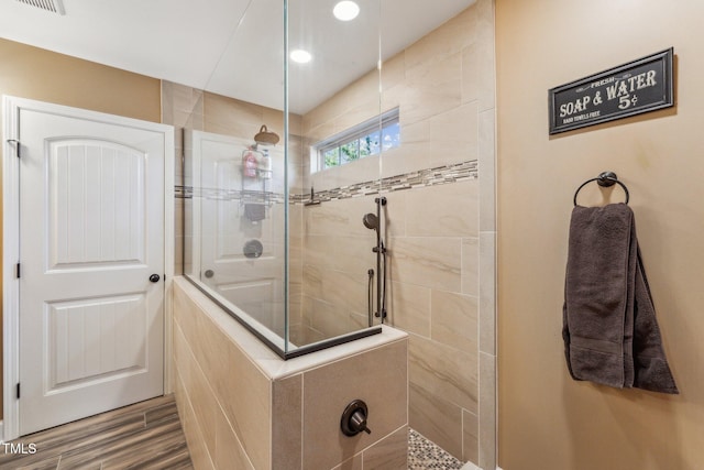 bathroom featuring wood-type flooring and tiled shower