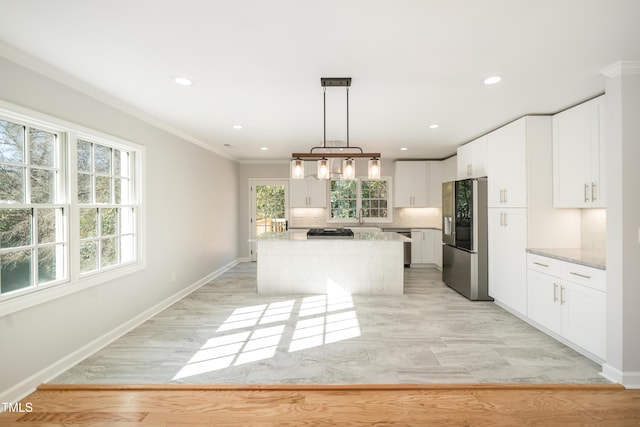 kitchen featuring a center island, hanging light fixtures, stainless steel fridge, light stone countertops, and white cabinets