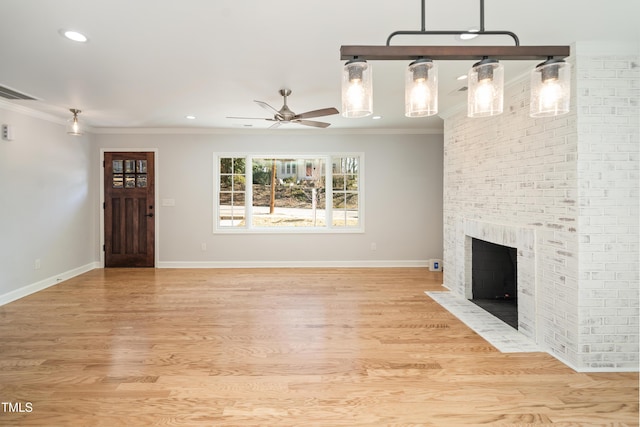 unfurnished living room with a brick fireplace, crown molding, and light hardwood / wood-style floors