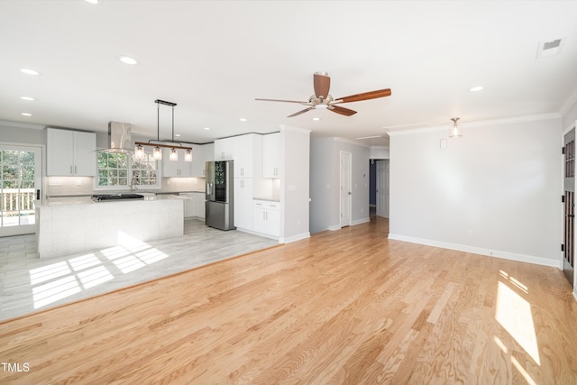 unfurnished living room with light hardwood / wood-style flooring, ornamental molding, and ceiling fan