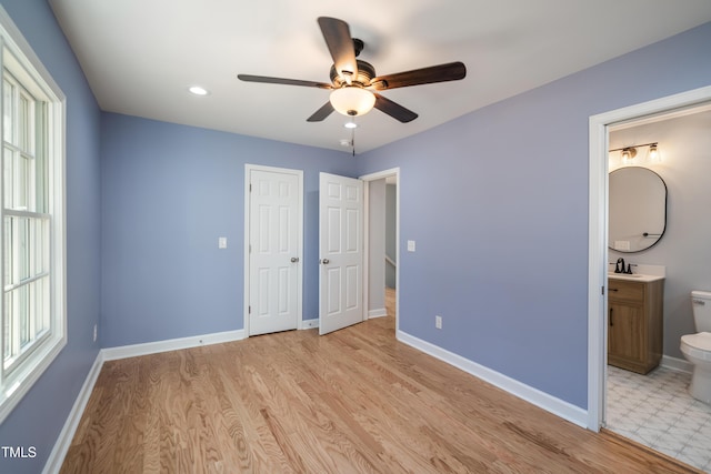 unfurnished bedroom with ensuite bathroom, sink, light hardwood / wood-style flooring, ceiling fan, and a closet