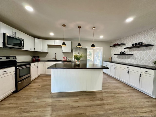 kitchen featuring appliances with stainless steel finishes, white cabinetry, decorative light fixtures, and sink