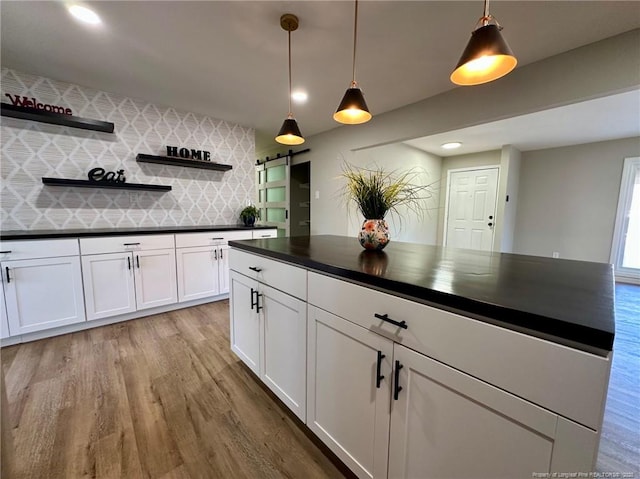 kitchen with light hardwood / wood-style floors, white cabinets, tasteful backsplash, and pendant lighting