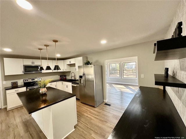 kitchen with appliances with stainless steel finishes, white cabinetry, pendant lighting, and a center island