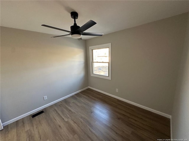 spare room with dark hardwood / wood-style flooring and ceiling fan