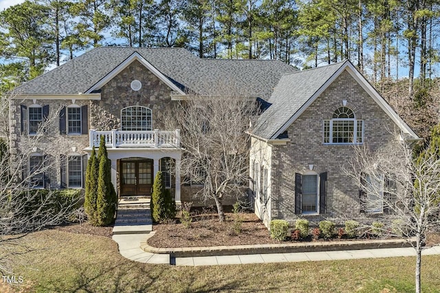 view of front facade featuring a front lawn, french doors, and a balcony