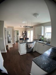 kitchen featuring dark countertops, a peninsula, white cabinetry, and stainless steel dishwasher