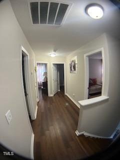 hallway featuring baseboards, visible vents, and dark wood-style flooring