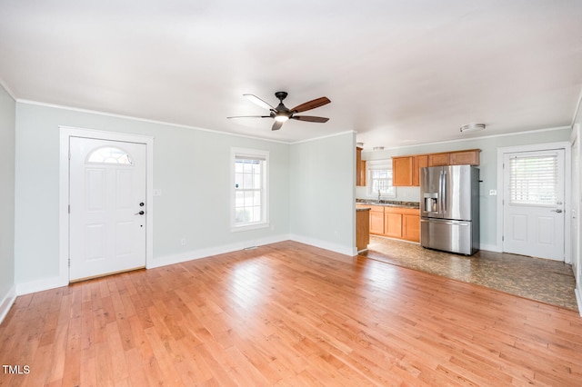 unfurnished living room with ceiling fan, light hardwood / wood-style floors, sink, and crown molding