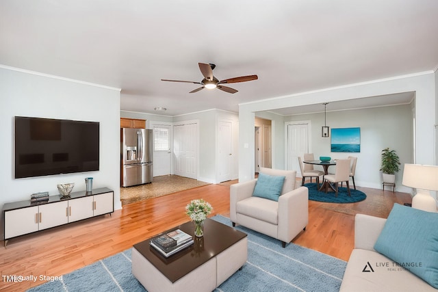 living room featuring ceiling fan, light wood-type flooring, and crown molding