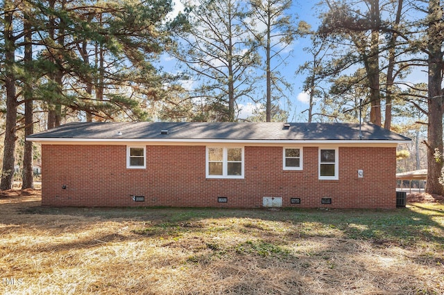 rear view of property with central air condition unit and a yard