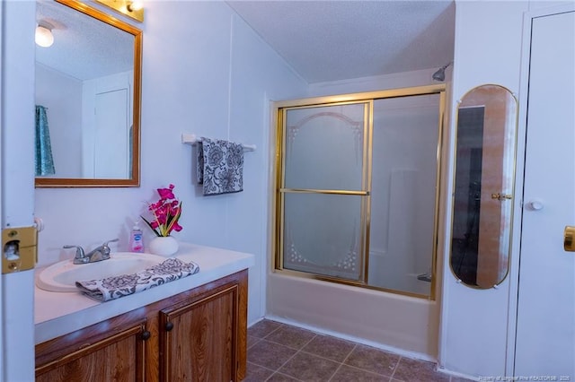 bathroom with combined bath / shower with glass door, a textured ceiling, and vanity