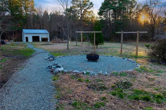 yard at dusk with an outdoor fire pit and an outbuilding