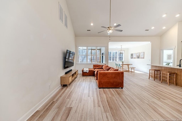 living room featuring ceiling fan with notable chandelier, sink, and light wood-type flooring