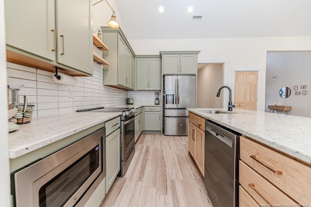 kitchen featuring light stone counters, stainless steel appliances, light hardwood / wood-style floors, and sink