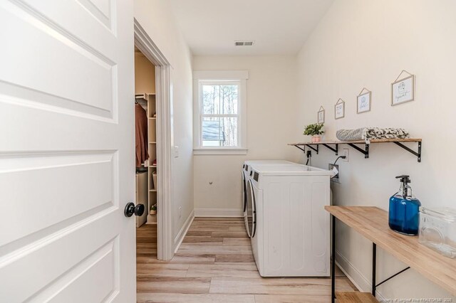 laundry room with washing machine and dryer and light hardwood / wood-style floors