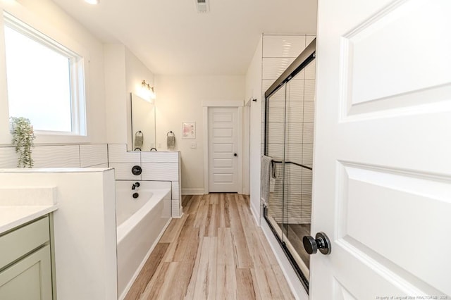 bathroom with shower with separate bathtub, vanity, and hardwood / wood-style flooring