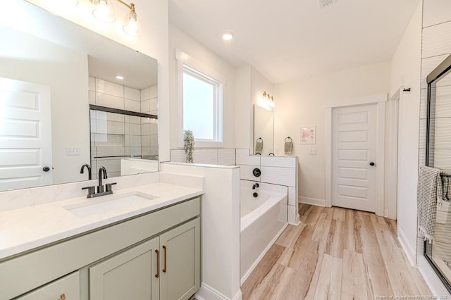 bathroom featuring plus walk in shower, vanity, and wood-type flooring