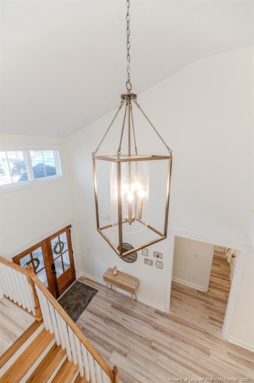 stairs featuring lofted ceiling, french doors, hardwood / wood-style flooring, and a notable chandelier