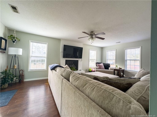 living room with a textured ceiling, ceiling fan, and dark hardwood / wood-style floors