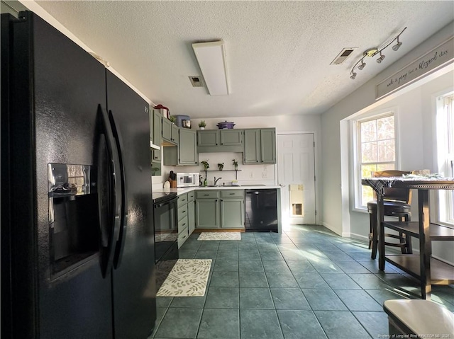 kitchen with black appliances, dark tile patterned floors, a textured ceiling, and sink